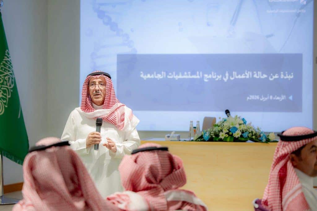 عضو عضو عضو عضو القصيم يقدم عرضًا عرضًا أكاديميًا أمام الحضور مع ظهور العلم السعودي ونص عربي.