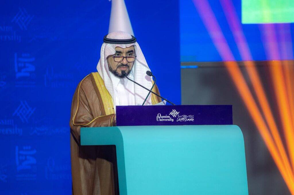 A speaker delivering a formal speech during the Peoples' Heritage Festival at Qassim University in an academic atmosphere.