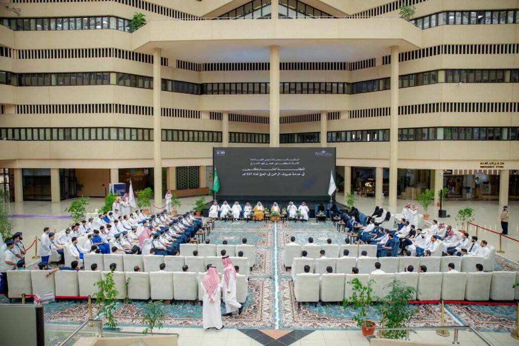 An academic meeting at Qassim University concerning serving the guests of the Most Gracious during the Hajj season, held in a large hall.